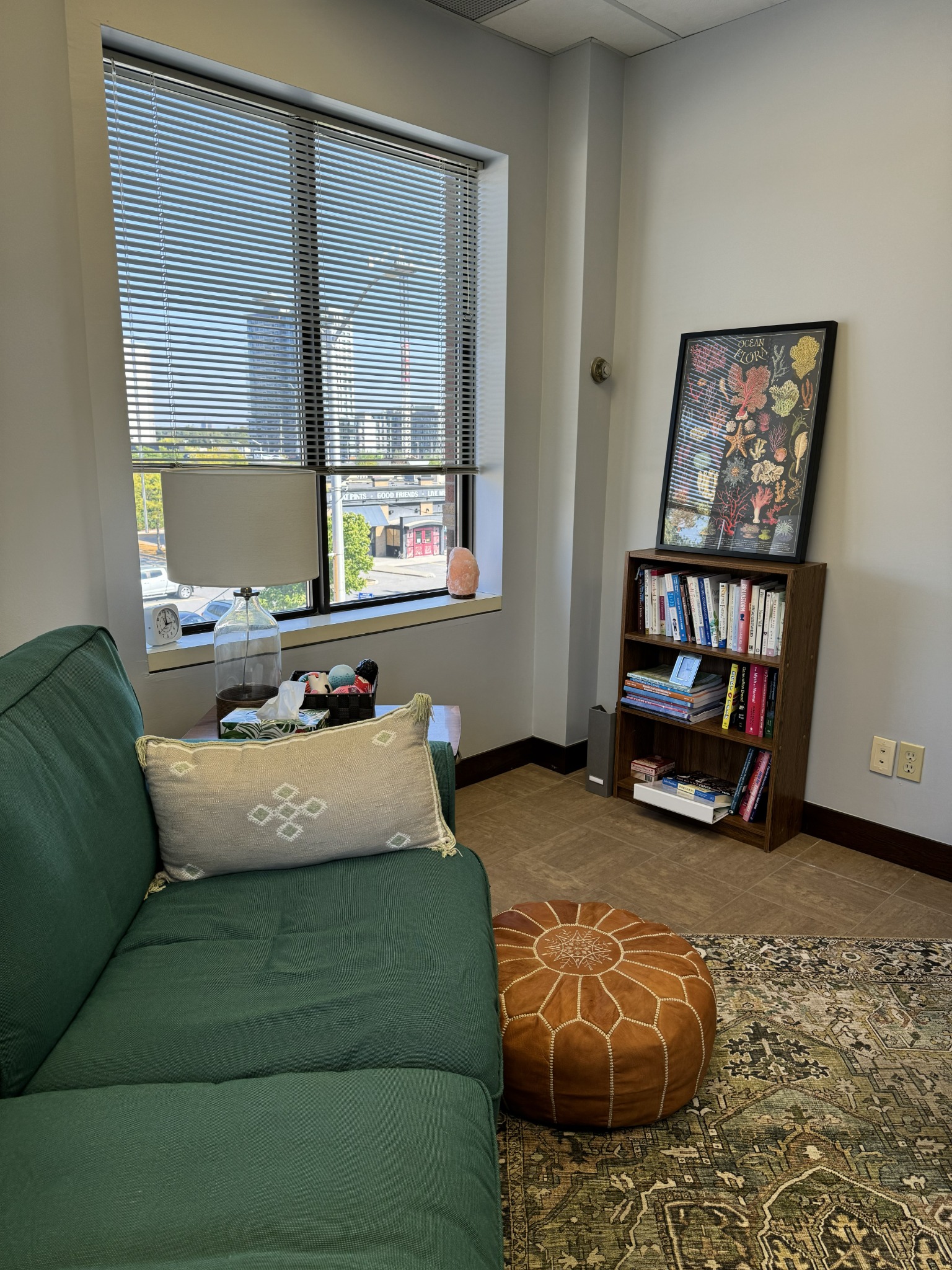 Welcoming therapy room with a green sofa, books, and natural light